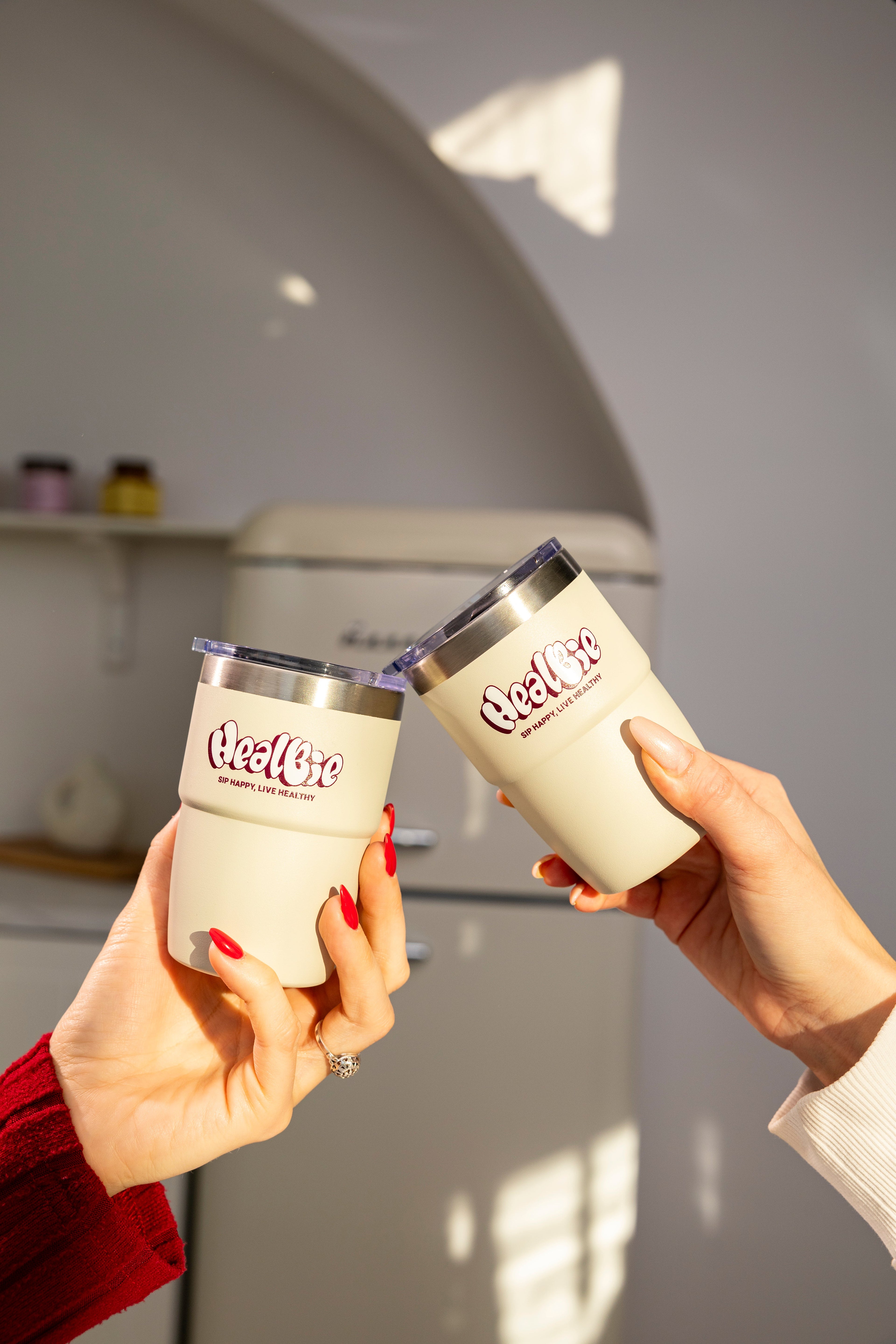 kubki termiczne do kawy i herbaty w jasnym kolorze w dłoni