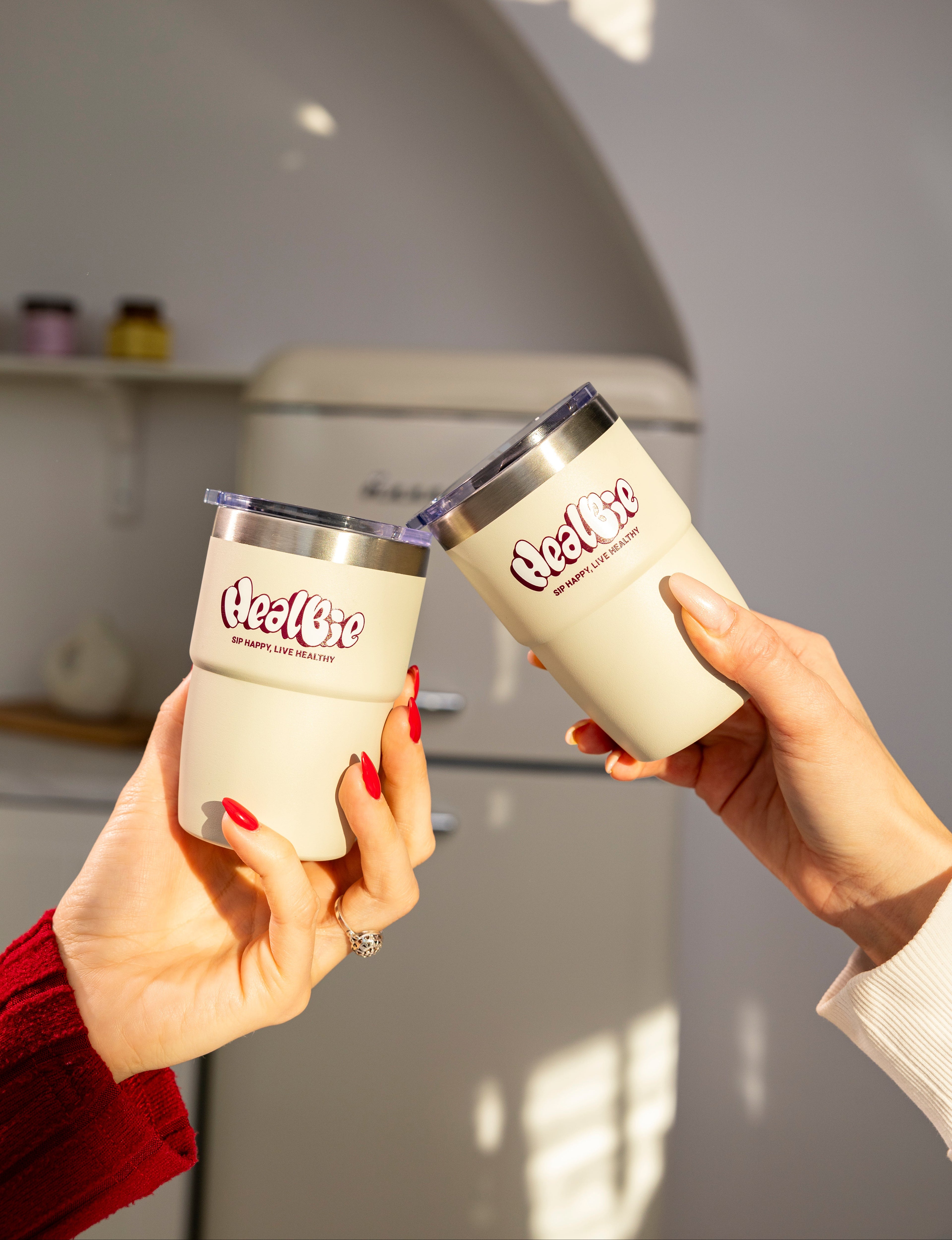 dwa kubki termiczne ze stali nierdzewnej o jasnym kolorze w dłoni 